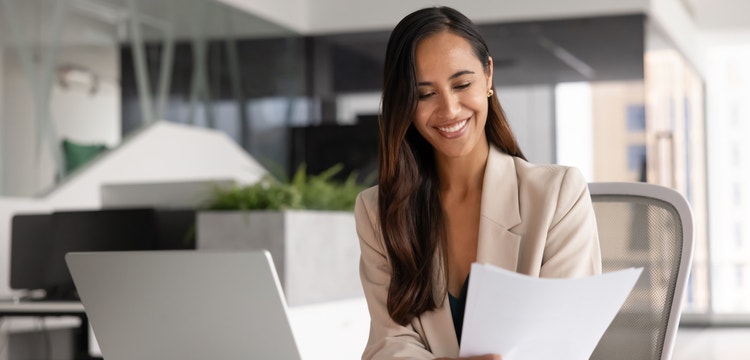 A woman smiling as she reviews a document